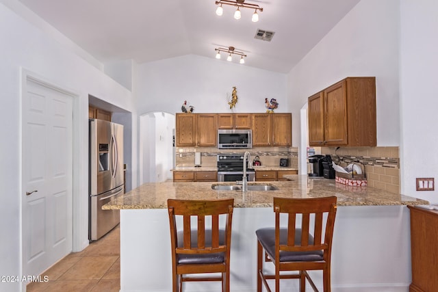 kitchen featuring tasteful backsplash, sink, a kitchen bar, stainless steel appliances, and vaulted ceiling