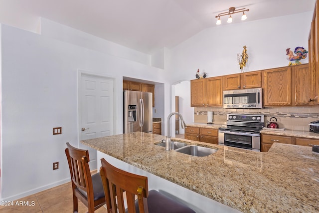 kitchen with lofted ceiling, sink, a kitchen bar, appliances with stainless steel finishes, and tasteful backsplash