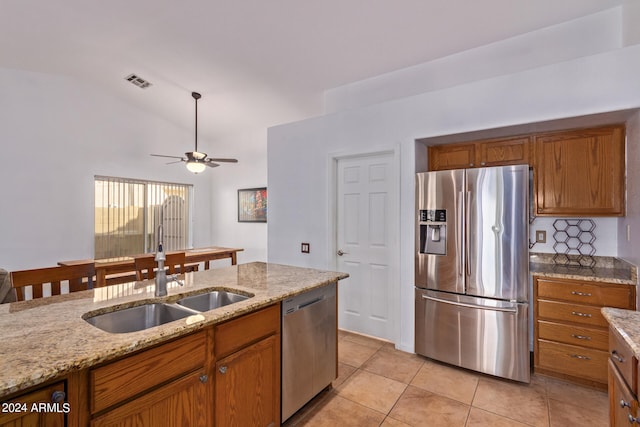 kitchen with lofted ceiling, sink, appliances with stainless steel finishes, light stone counters, and ceiling fan