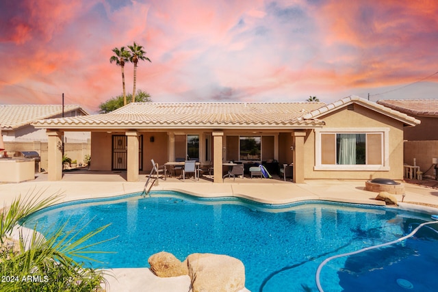 pool at dusk with a patio area