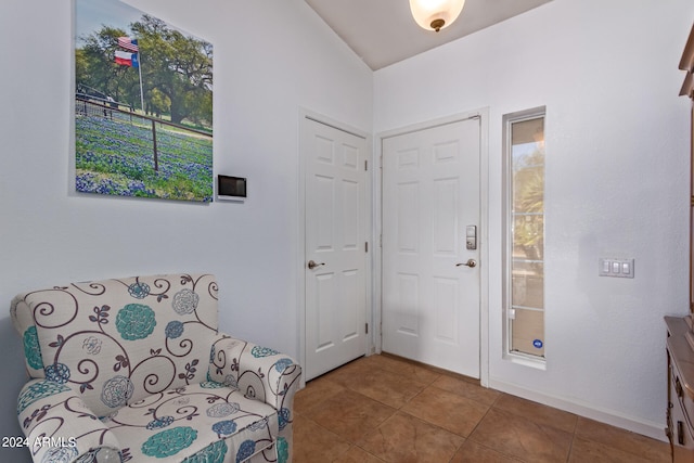 foyer entrance with tile patterned floors and vaulted ceiling