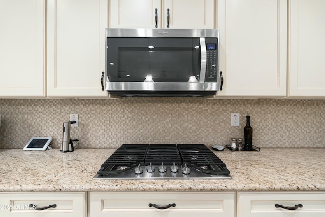 room details with light stone countertops, white cabinetry, stainless steel appliances, and backsplash