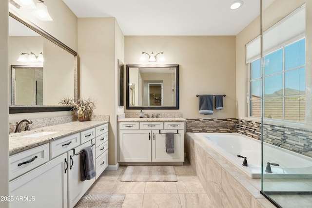 full bathroom featuring a bath, tile patterned flooring, two vanities, and a sink