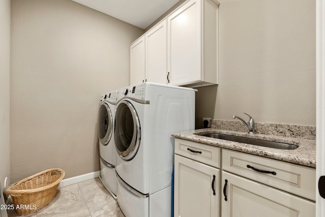 washroom featuring washer and dryer, cabinet space, a sink, and baseboards