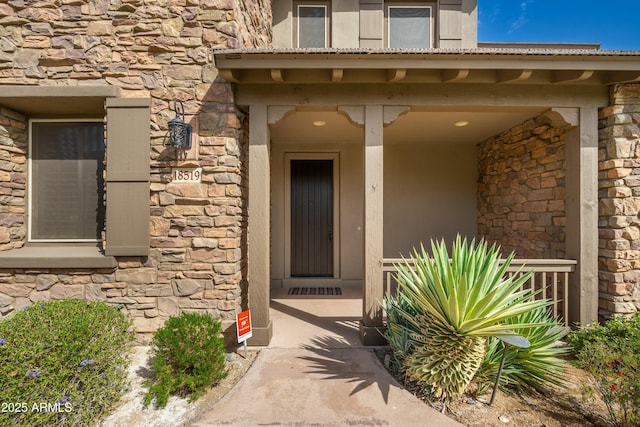 property entrance with stone siding and a porch