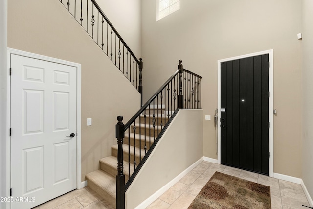 entryway featuring stairway, a high ceiling, and baseboards