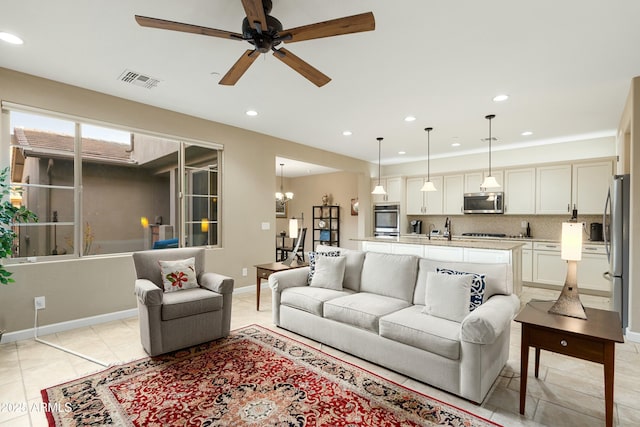 living room with light tile patterned floors, recessed lighting, visible vents, baseboards, and ceiling fan with notable chandelier