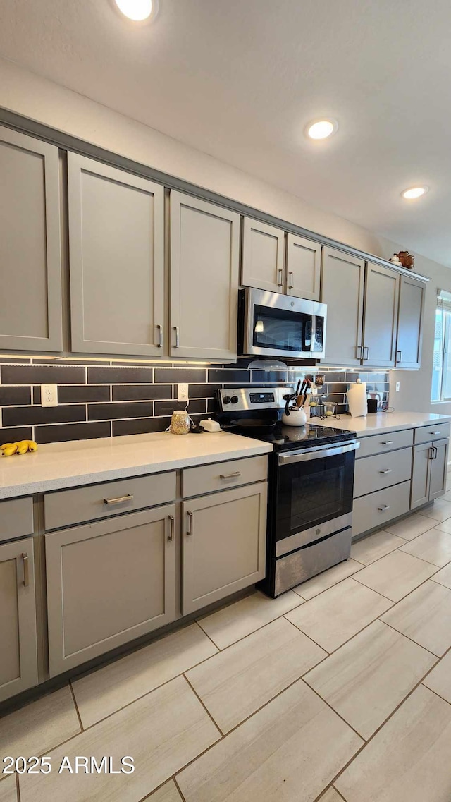 kitchen featuring backsplash, gray cabinetry, and appliances with stainless steel finishes