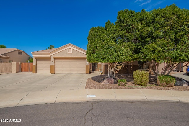 view of front facade featuring stucco siding, driveway, fence, an attached garage, and a tiled roof