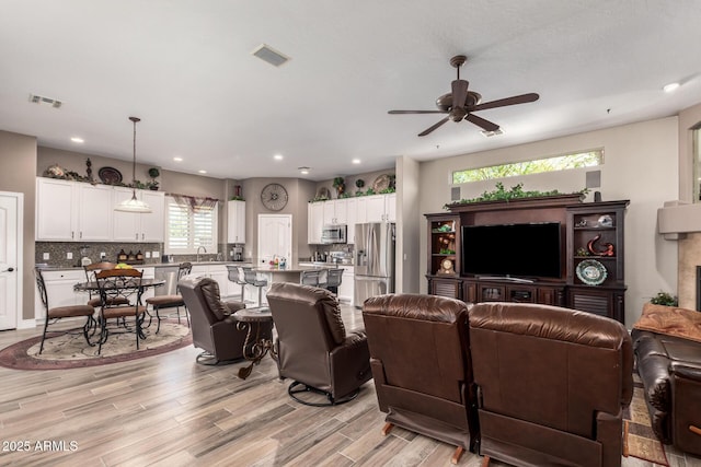 living room featuring recessed lighting, visible vents, light wood-style flooring, and a ceiling fan