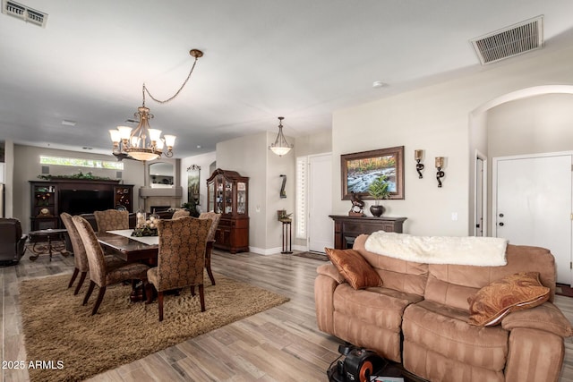 dining space featuring arched walkways, visible vents, a fireplace, and wood finished floors