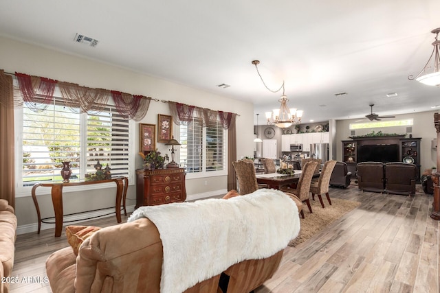 dining area with visible vents, ceiling fan with notable chandelier, baseboards, and light wood-style floors