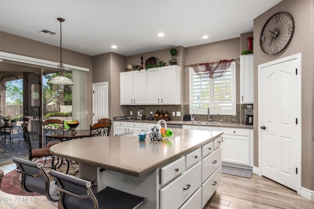 kitchen featuring a sink, light wood-style floors, tasteful backsplash, and a center island