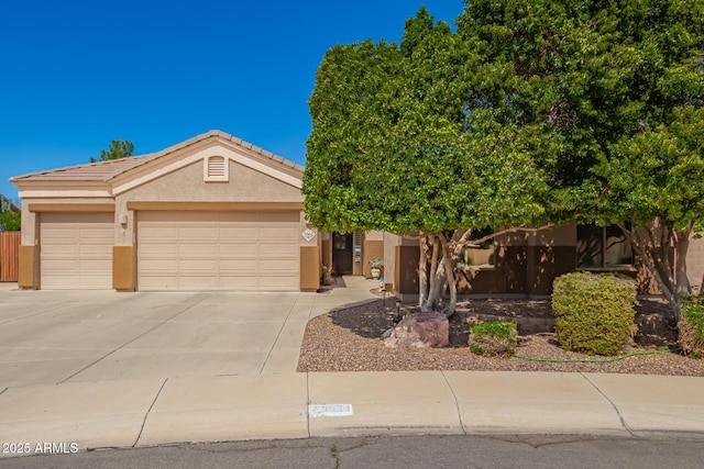 view of front of property with a garage, a tile roof, concrete driveway, and stucco siding