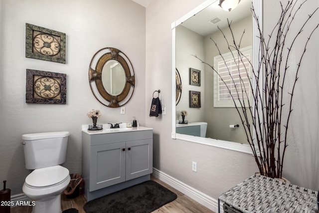 full bath with visible vents, baseboards, toilet, wood finished floors, and vanity