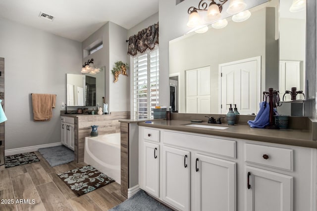 full bathroom with visible vents, vanity, a garden tub, and wood tiled floor