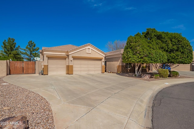 view of front facade featuring stucco siding, a gate, a tile roof, concrete driveway, and a garage