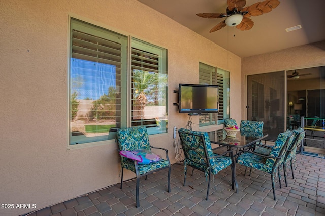 view of patio with outdoor dining area, visible vents, and ceiling fan