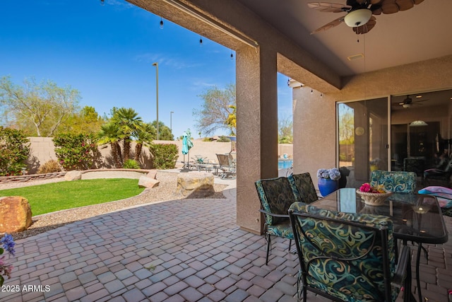 view of patio with outdoor dining area, a ceiling fan, and a fenced backyard