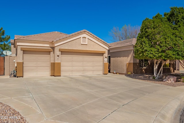 view of front of house featuring a tile roof, an attached garage, driveway, and stucco siding