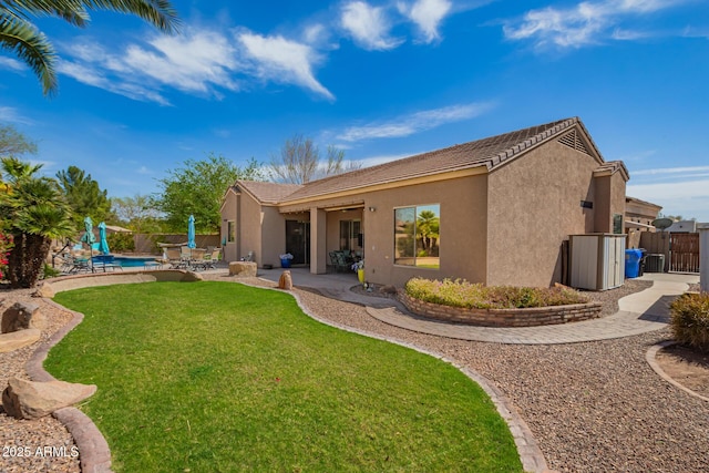 back of property with a gate, fence, a yard, stucco siding, and a patio area