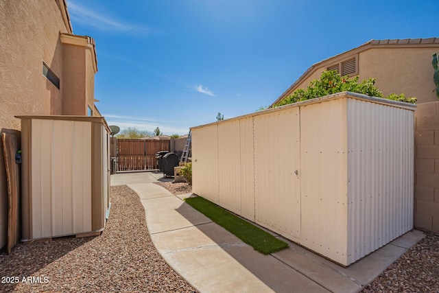 view of side of property featuring a storage unit, stucco siding, a gate, fence, and an outdoor structure