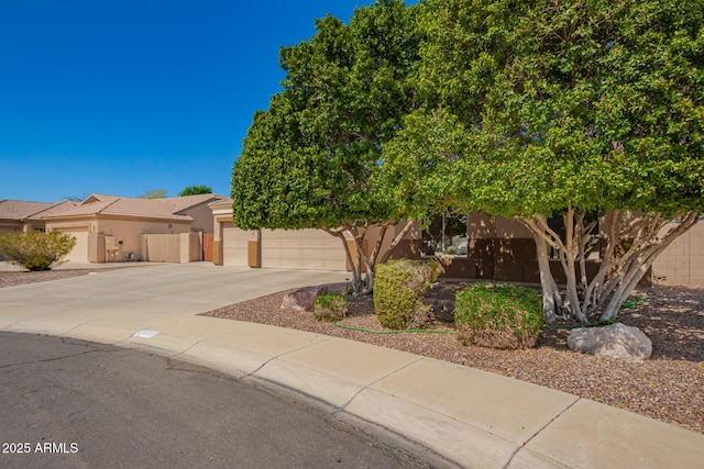 view of front of property with stucco siding, an attached garage, concrete driveway, and fence