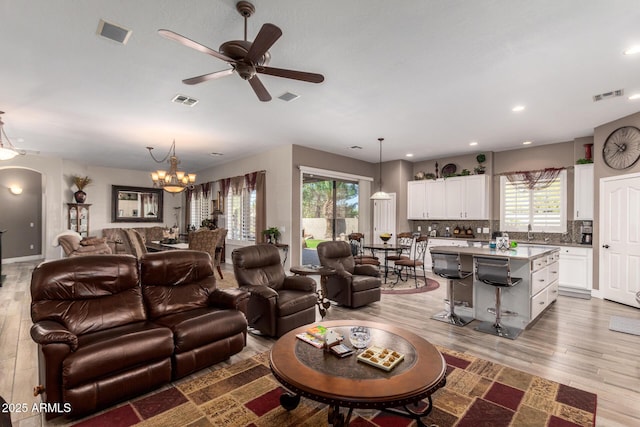 living room with wood finished floors, visible vents, and arched walkways