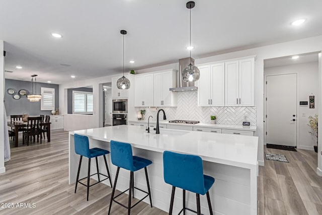 1501 E Rakestraw Ln, Gilbert, AZ 85298 - kitchen with wall chimney exhaust hood, a sink, light wood-type flooring, white cabinets, and stainless steel appliances
