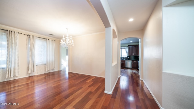 spare room with dark hardwood / wood-style flooring and a notable chandelier