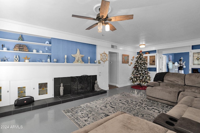 living room with ceiling fan, crown molding, and a tile fireplace