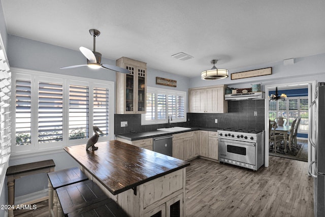 kitchen featuring ceiling fan with notable chandelier, stainless steel appliances, extractor fan, sink, and hardwood / wood-style floors