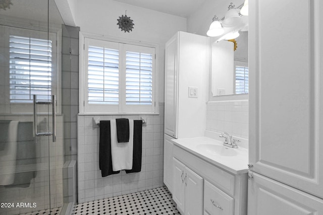 bathroom featuring tile patterned flooring, vanity, a shower with shower door, and tile walls