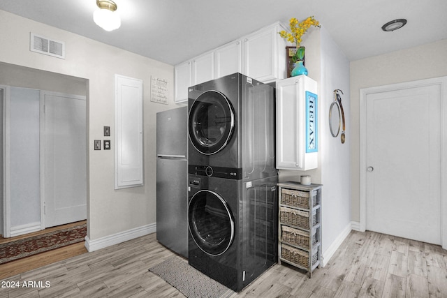 clothes washing area featuring light hardwood / wood-style flooring and stacked washer and clothes dryer