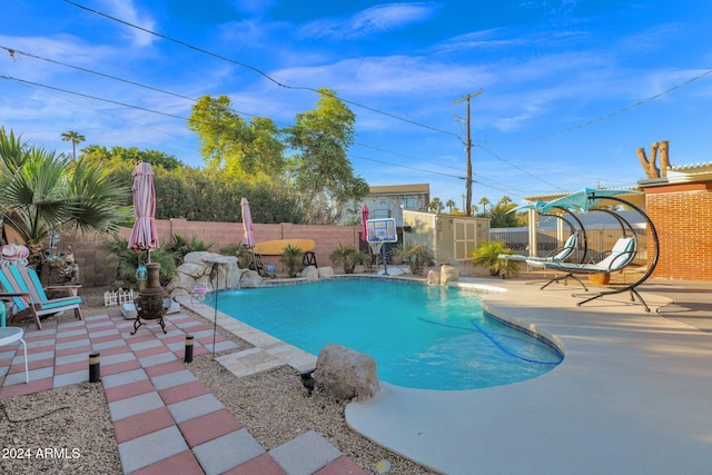 view of swimming pool with a patio area, pool water feature, and a shed