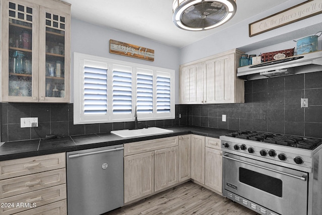 kitchen with appliances with stainless steel finishes, tasteful backsplash, sink, light brown cabinets, and light hardwood / wood-style floors