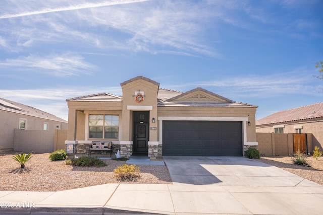 view of front facade with a garage, concrete driveway, stone siding, fence, and stucco siding