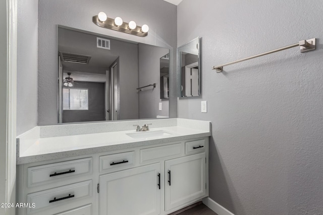 bathroom with visible vents, vanity, and a textured wall