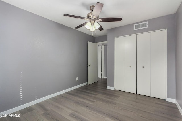 unfurnished bedroom with visible vents, wood finished floors, a closet, baseboards, and ceiling fan