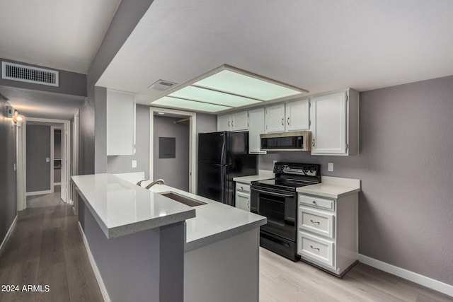 kitchen with black appliances, kitchen peninsula, sink, and light hardwood / wood-style floors