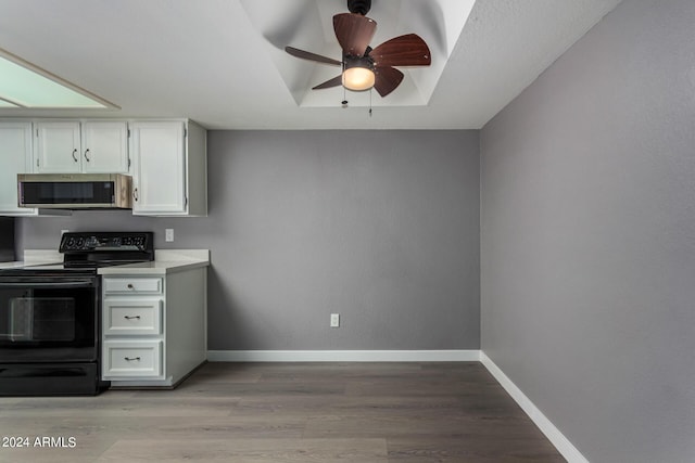 kitchen featuring black electric range oven, stainless steel microwave, baseboards, a raised ceiling, and ceiling fan