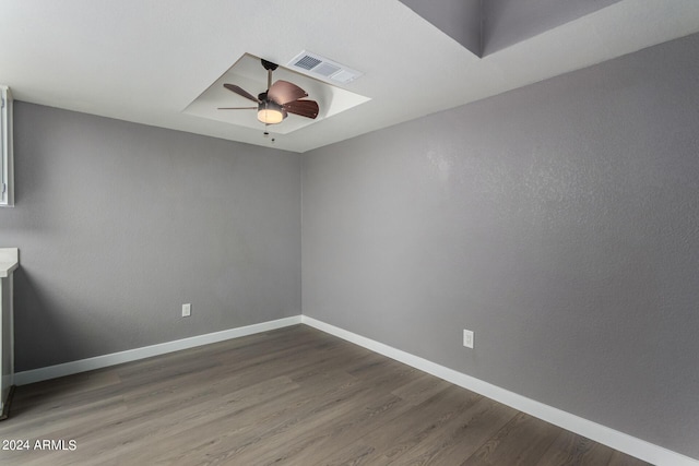 unfurnished room with wood finished floors, a ceiling fan, visible vents, baseboards, and a raised ceiling