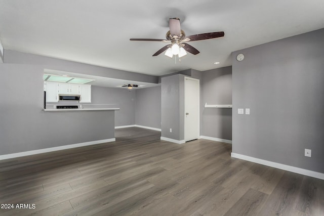 unfurnished living room with baseboards, ceiling fan, and dark wood finished floors