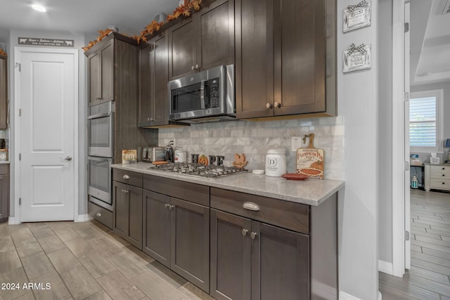 kitchen featuring dark brown cabinetry, decorative backsplash, stainless steel appliances, and light hardwood / wood-style flooring