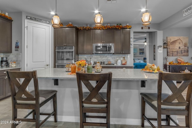 kitchen featuring a breakfast bar area, a kitchen island, light stone countertops, pendant lighting, and appliances with stainless steel finishes