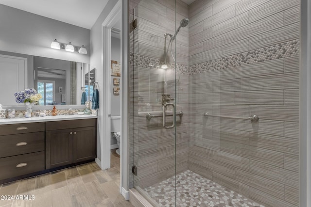 bathroom featuring vanity, toilet, wood-type flooring, and a shower with shower door