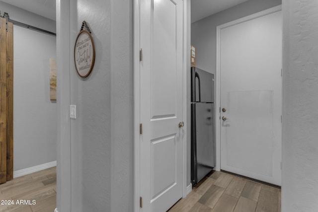 hallway with a barn door and light hardwood / wood-style floors