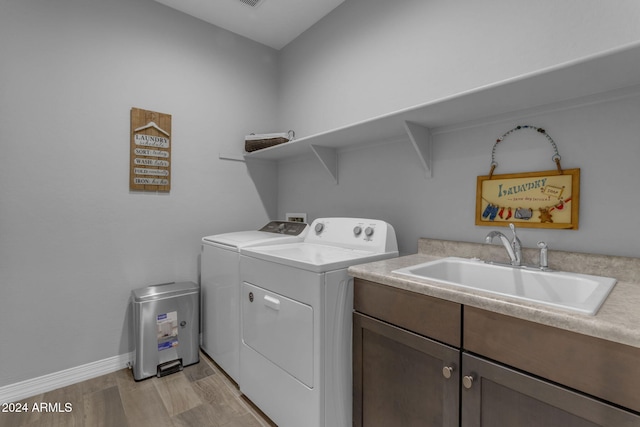 laundry room featuring cabinets, separate washer and dryer, sink, and light wood-type flooring