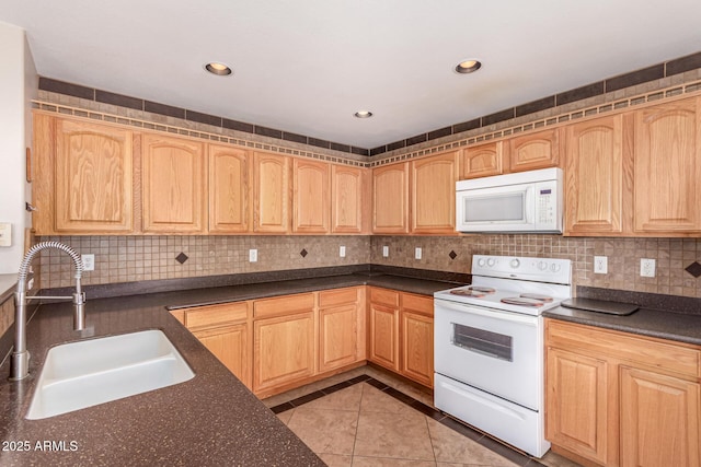 kitchen featuring a sink, white appliances, dark countertops, and light brown cabinetry