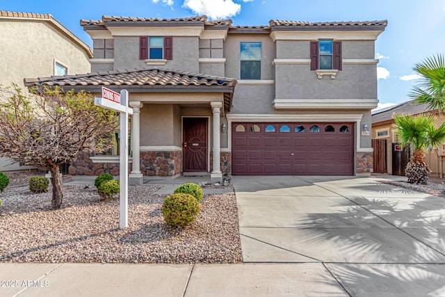 mediterranean / spanish home featuring stone siding, stucco siding, driveway, and an attached garage